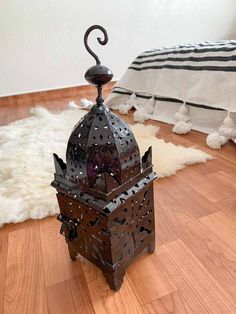 an iron lamp on the floor next to a bed with white furnishing and rugs