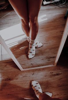 two people standing in front of a mirror with their feet on the floor and one person wearing socks