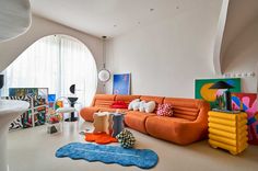 a living room filled with lots of furniture and art on the walls, along with an arched window