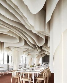 a dining room with tables and chairs covered in white paper hanging from the ceiling above