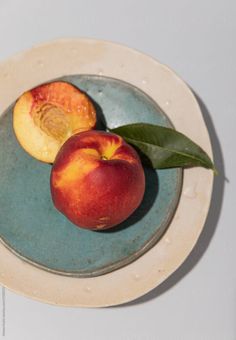 two peaches on a plate with leaves