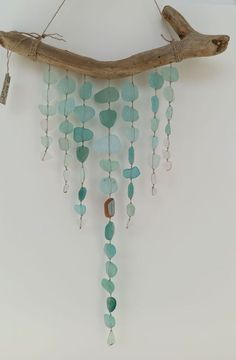 a piece of driftwood with sea glass beads hanging from it's side on the wall