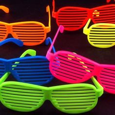 four pairs of neon colored sunglasses on a black background