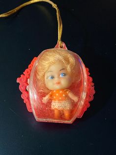 a little doll ornament hanging on a black surface