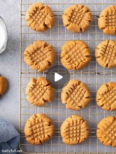 peanut butter cookies cooling on a wire rack next to a glass of milk and spoon