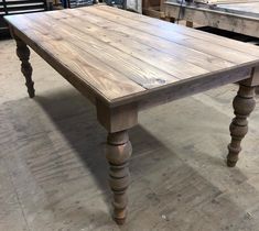 a wooden table sitting in the middle of a room with other woodworking equipment behind it