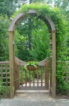 a wooden gate with a potted plant in the center and greenery around it