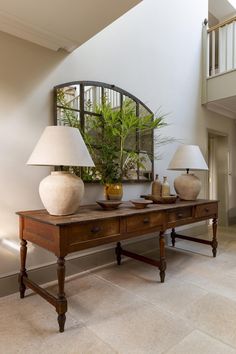 a table with two lamps on top of it next to a mirror and lamp shade