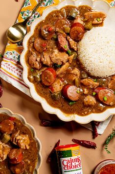 a plate with rice, meat and vegetables next to two bowls filled with sauces