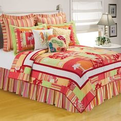 a bed with colorful comforters and pillows in a room