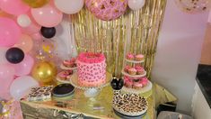 a table topped with cakes and desserts covered in pink, gold and black frosting