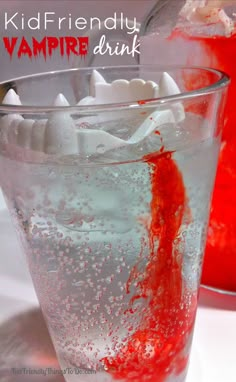 a glass filled with liquid and ice next to a jar