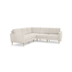 a white sectional couch sitting on top of a white floor next to a wooden leg chair