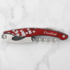 a red and white flowered pocket knife on a marble surface