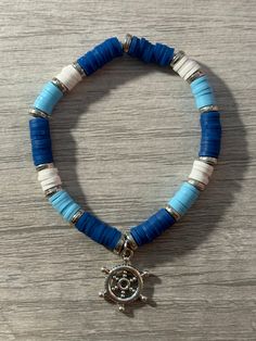 a blue and white beaded bracelet with a silver turtle charm on top of it