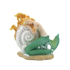 a figurine of a mermaid sitting on top of a white and green shell