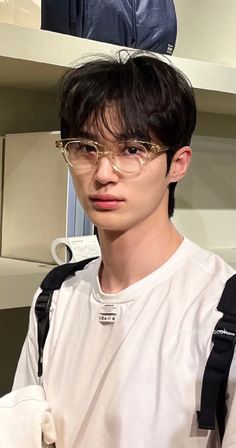 a young man with glasses and a backpack on his shoulder is looking at the camera