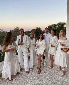 a group of people standing next to each other in front of a building at sunset