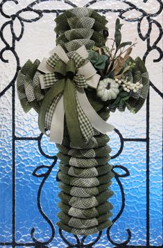 a green wreath with white flowers and greenery tied to it in front of a stained glass window