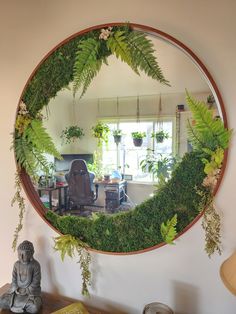 a mirror that has some plants on it and a buddha statue in front of it