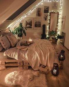 an attic bedroom with lights strung above the bed and rugs on the wooden floor