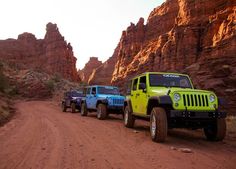 four jeeps are parked on the side of a dirt road