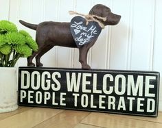 a welcome sign with a dog on it next to some flowers and potted plants