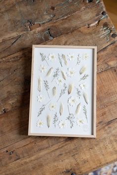 some white flowers and leaves are on a wooden table next to a piece of wood