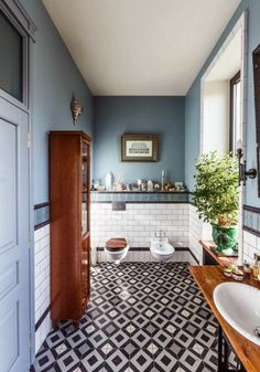 a bathroom with blue walls and black and white tile flooring is pictured in this image