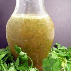 a glass bottle filled with liquid surrounded by green leaves