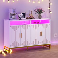 a pink and white cabinet with lights on the wall above it, in front of a purple background