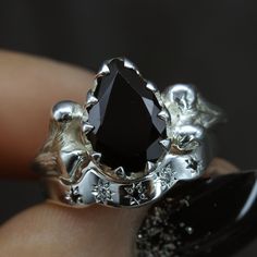 a close up of a person's hand holding a ring with a black stone