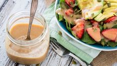 a salad with dressing on the side and a spoon in it next to a glass jar