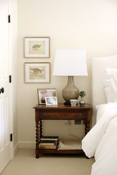 a bed room with a neatly made bed next to a lamp and pictures on the wall