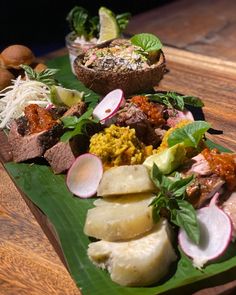 a wooden table topped with lots of different types of food on top of green plates