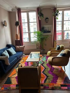 a living room with couches, chairs and a rug on the floor in front of two windows