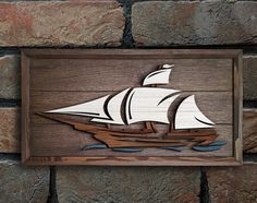 a wooden sign with a ship painted on it's front and back sides, mounted to a brick wall