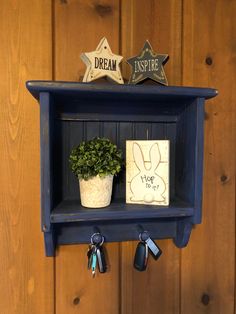 a blue shelf with key hooks and a potted plant on top, hanging from the wall