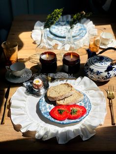 a plate with bread and tomatoes on it sitting on a table next to tea cups