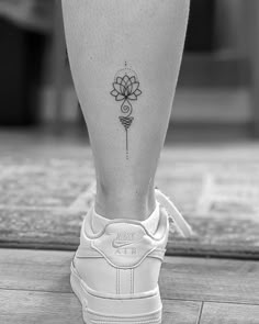 a black and white photo of a person's foot with a flower tattoo on it