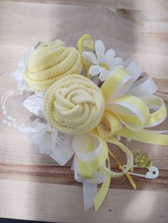 a yellow and white corsage with flowers on it sitting on a wooden table