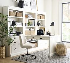 a home office with white bookcases and wicker baskets on the desk area