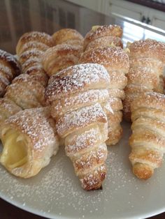 several croissants on a plate with powdered sugar