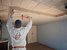 a man in white jumpsuit painting a ceiling