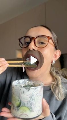 a woman holding chopsticks in her mouth while eating sushi from a bowl