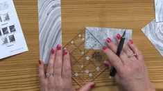 a woman with red nail polish is cutting up some papers on a wooden table next to a pair of scissors