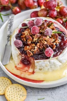 a cheese dish with grapes and walnuts on top, next to some crackers