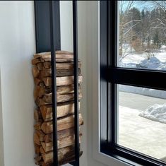 a stack of firewood sitting next to a window in a room filled with snow