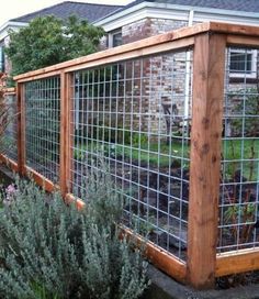 a fenced in garden area with plants and flowers