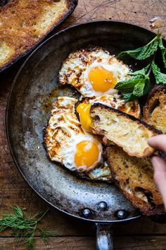 an egg is being fried on toast in a skillet with fresh herbs and butter